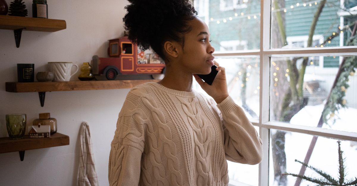 Woman on a phone call beside a window in a quiet room