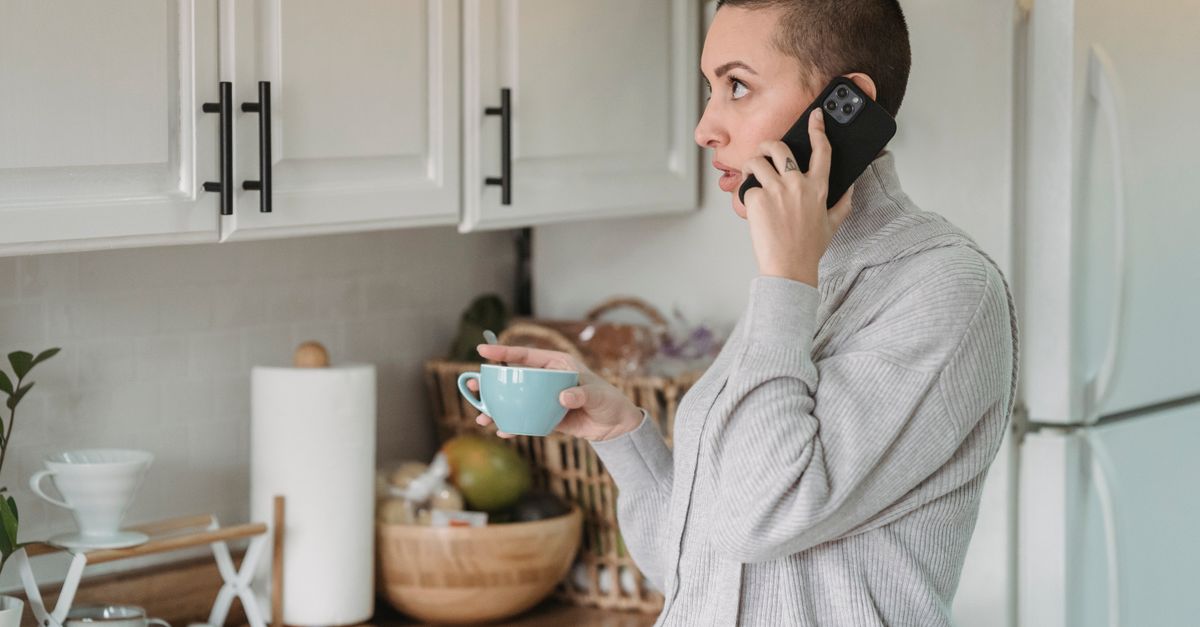 Woman on the phone in a kitchen reporting early pregnancy light bleeding to her IVF clinic
