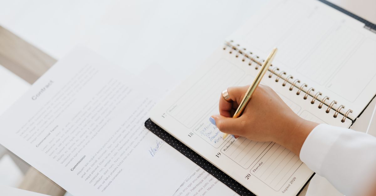Hand writing notes in a spiral planner before calling a clinic about bleeding after IVF