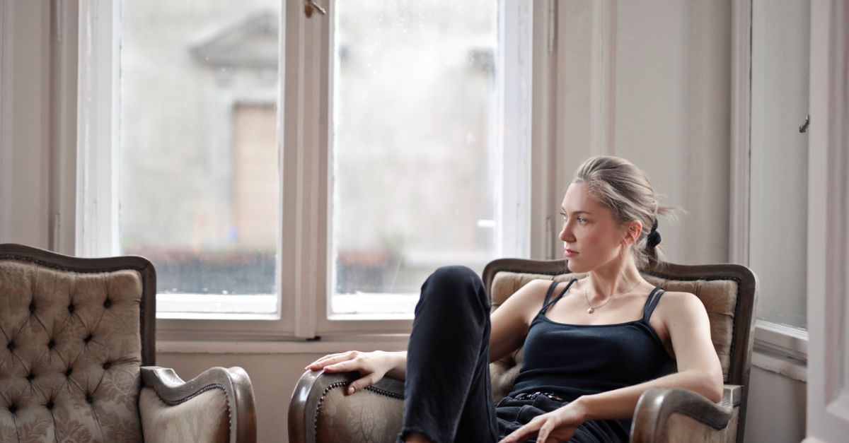 Woman sitting quietly in an armchair beside a bright window in the morning