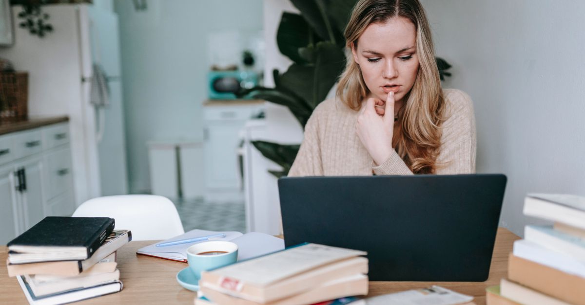 Woman at a kitchen table with a laptop and books, comparing what different pages claim about spotting