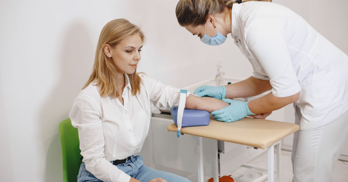 Woman seated in a clinic while a nurse takes a blood sample during frozen transfer cycle monitoring