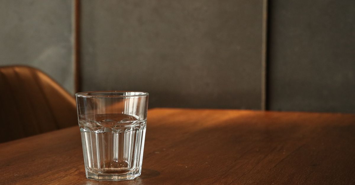 A plain glass of water on a wooden table, the bladder prep behind transfer pain
