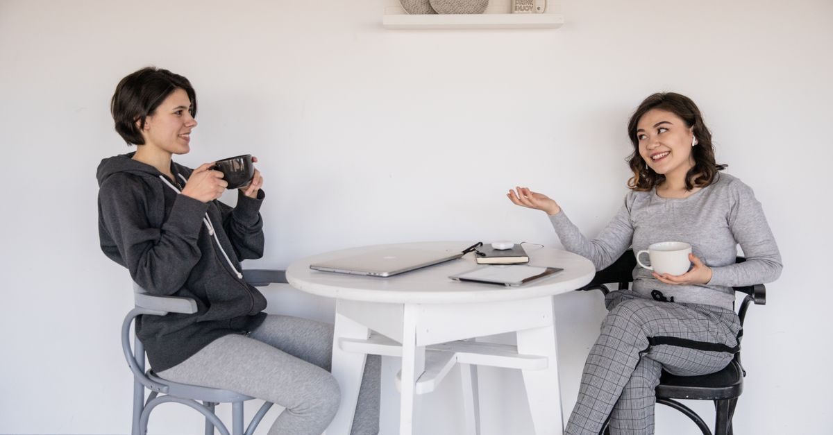 Two women talking across a bright table about spotting and what implantation bleeding looks like